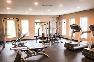 Una palestra con diverse attrezzature per esercizi, ampie finestre e un tapis roulant.