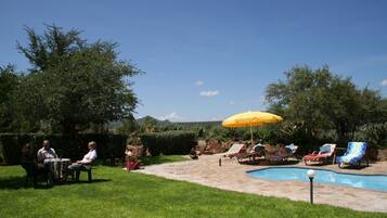 Una piscina al aire libre, sombrillas, sillones reclinables de piscina