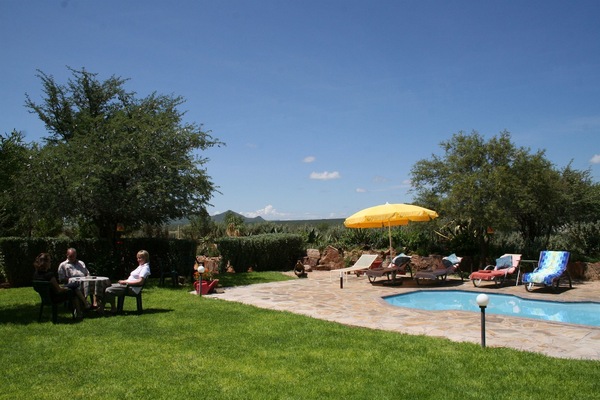 Een buitenzwembad, parasols bij het zwembad en ligstoelen