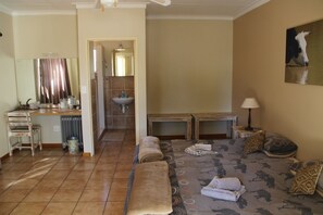 A room with a bed, a small table, a chair, a radiator, a sink, and a mirror.