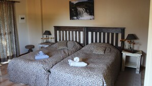 Ein Hotelzimmer mit zwei Betten, einem Bild eines Wasserfalls an der Wand und einem Vorhang mit Leopardenmuster.