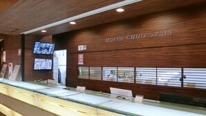 A hotel reception area with a wooden wall, a reception desk, and a glass display case. - Hotel Chuo Oasis (Osaka)