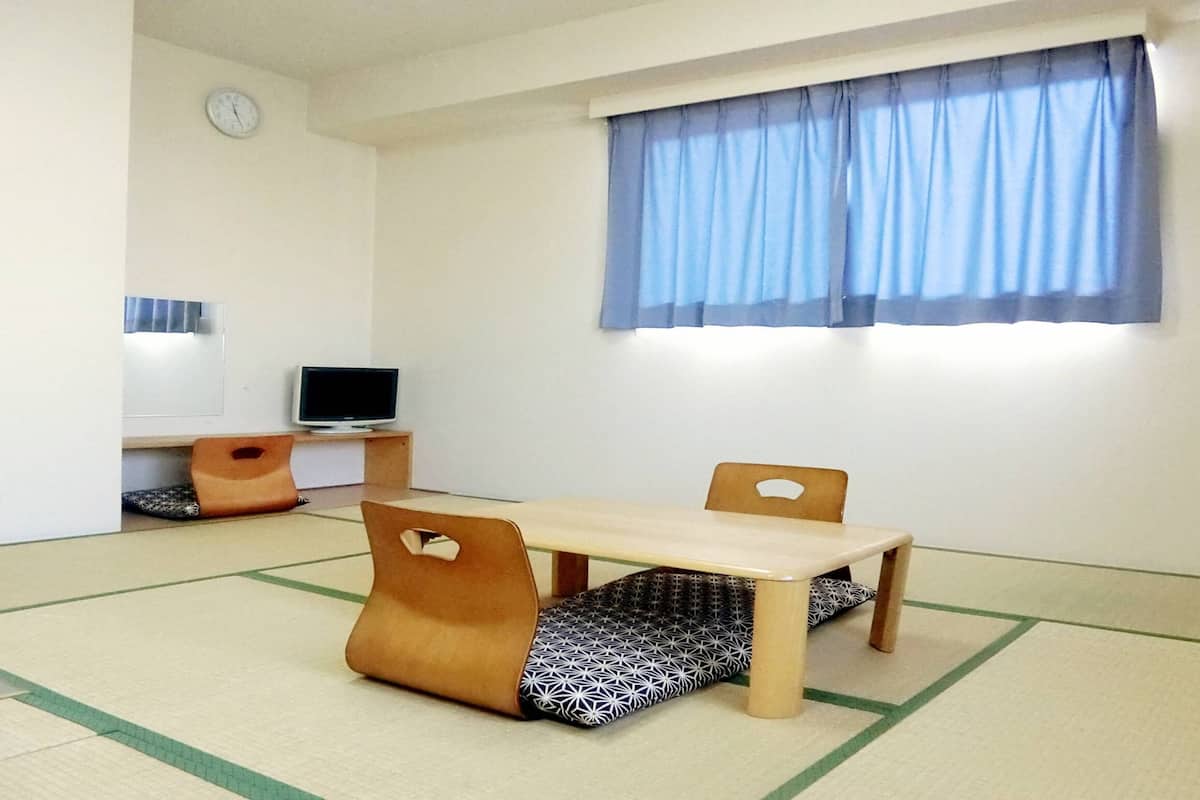 Une pièce avec une table en bois, deux chaises, un téléviseur et une horloge au mur.