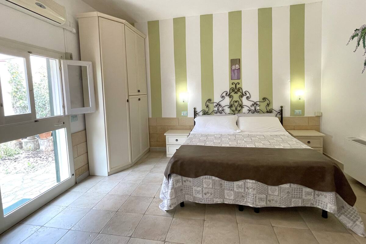 A bedroom with a bed, a wardrobe, a television, and a window.