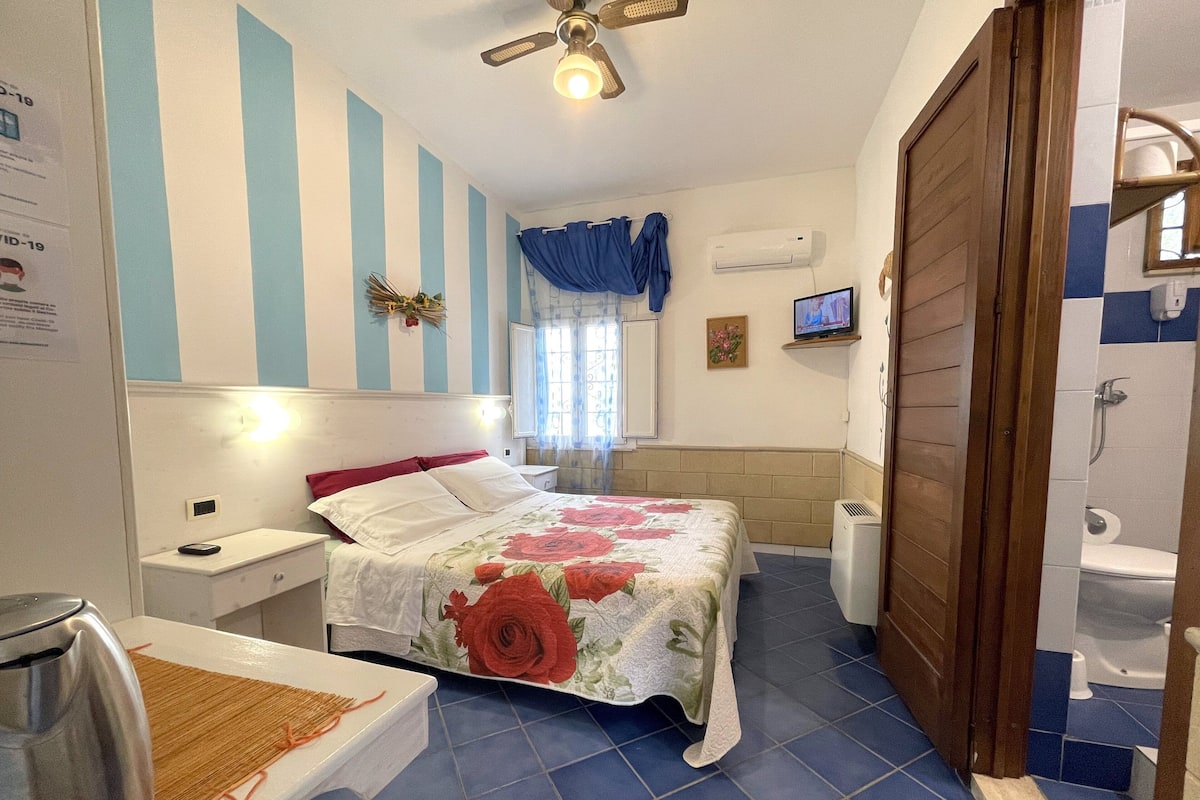 A bedroom with a bed, bedside table, and a TV.