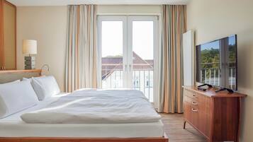 Ett hotellrum med en säng, en tv-apparat på en byrå i trä och utsikt över byggnader genom fönstret.