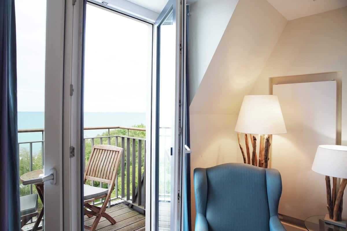 Une chambre avec un balcon, une chaise et une lampe.