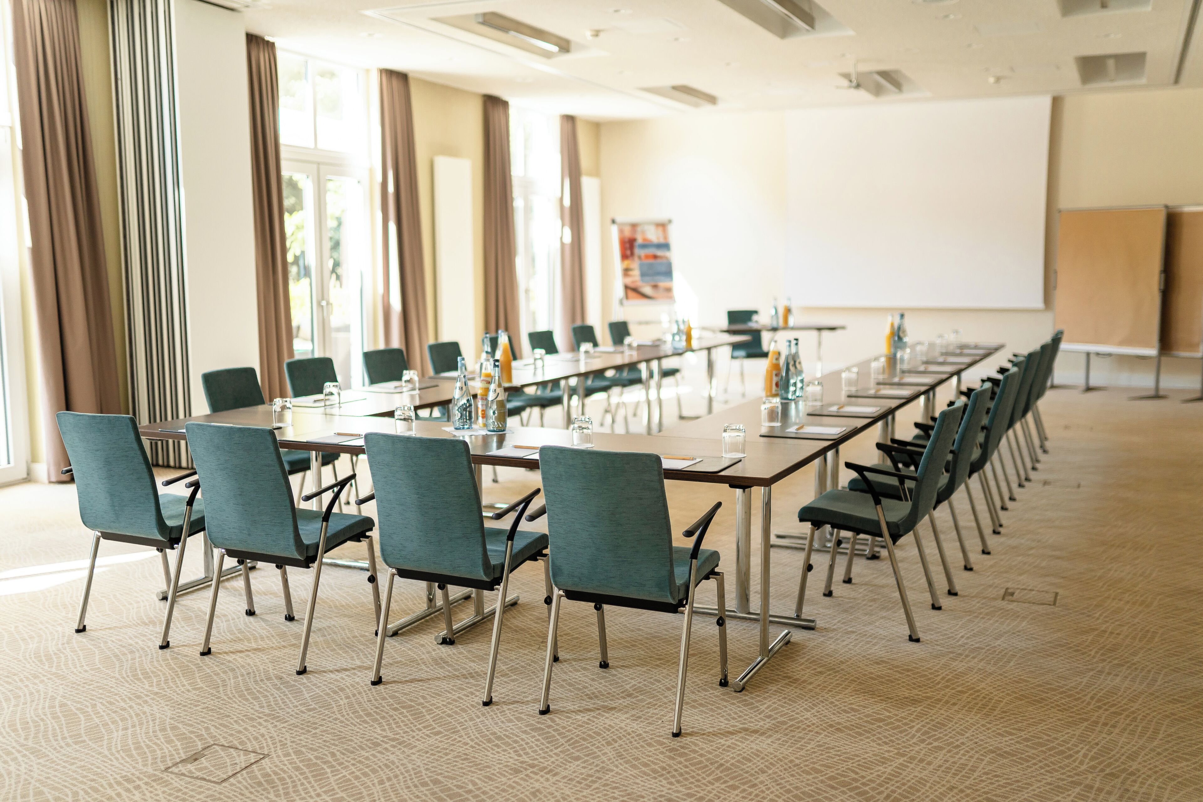A conference room with a long table, chairs, and a projector screen.