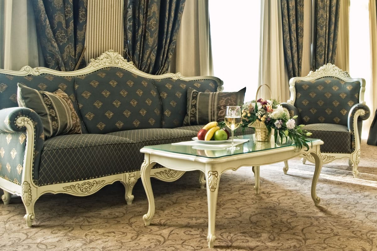A classic room with a sofa, armchair, and a small table with fruit and flowers.
