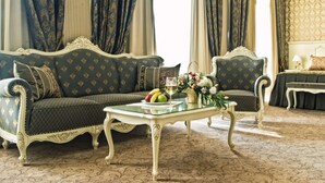 Habitación clásica con sofá, sillón y una mesita con frutas y flores.