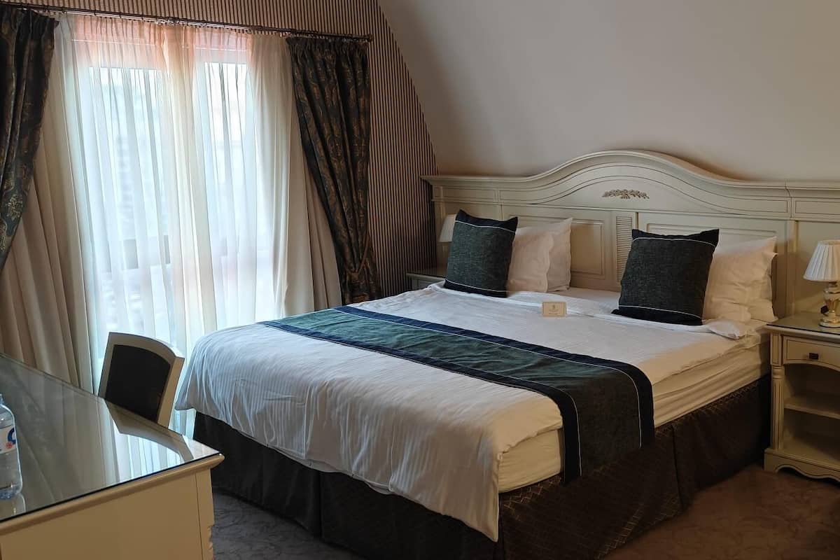 A hotel room with a bed, bedside tables, a chair, and a desk.