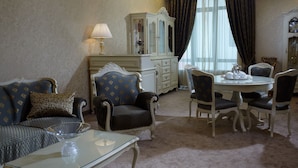 Una habitación con sofá, sillones, una mesa de comedor con sillas, un aparador y una lámpara.