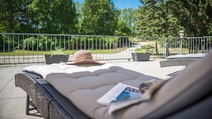 A sun lounger with a hat and magazine, a railing, and potted plants. - Hotel Mukran (Sassnitz)