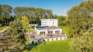 A hotel with a flat roof, multiple windows, and a patio area with outdoor furniture. - Hotel Mukran (Sassnitz)