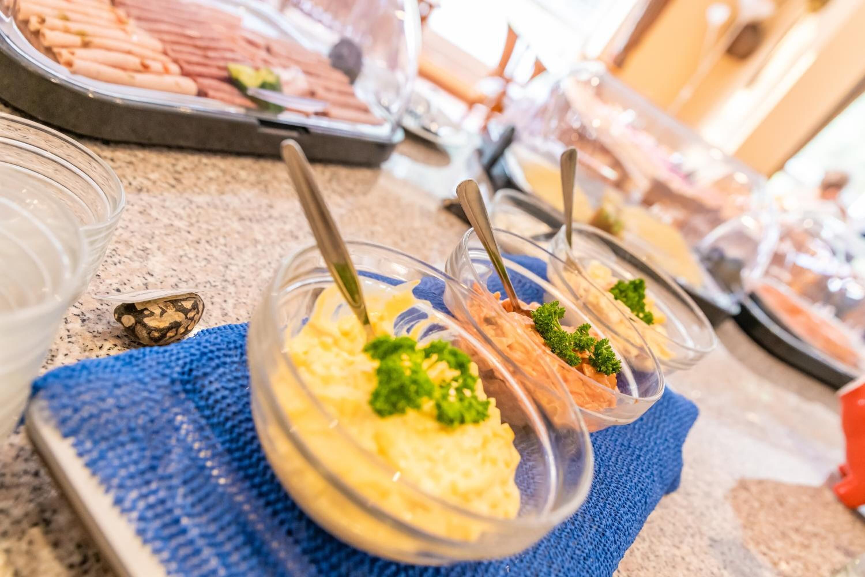 A buffet with various food items in clear containers, including a dish with a green garnish.
