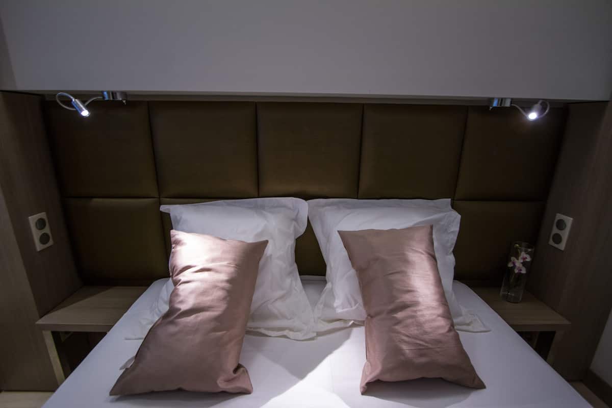 A bed with a headboard, two pillows, and a bedside table with a vase.
