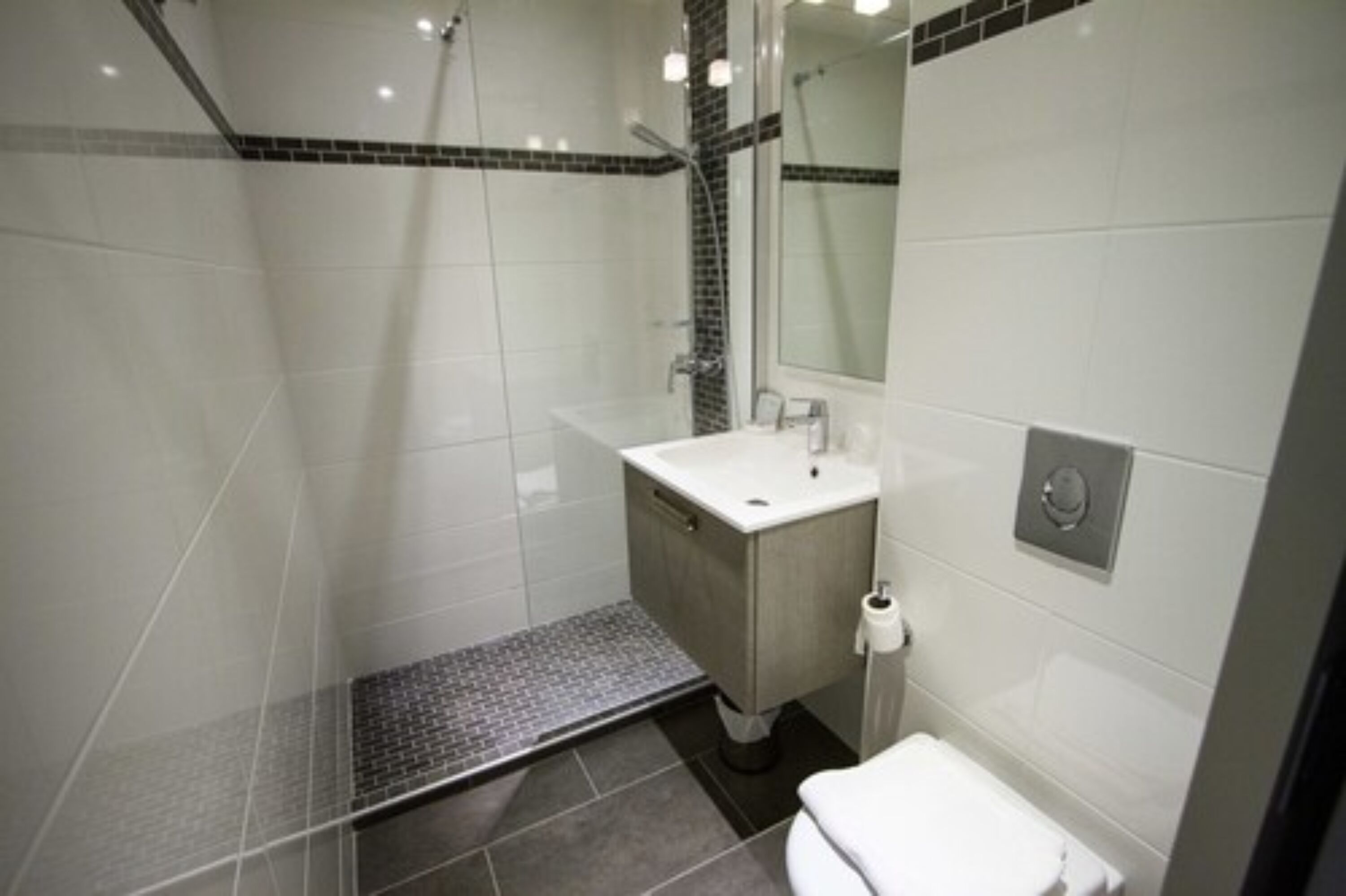 A modern bathroom with a shower, toilet, and sink.