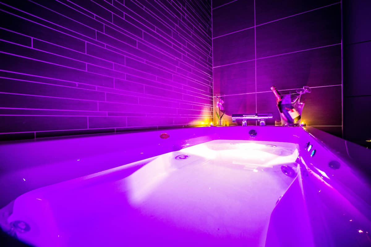A modern indoor pool area with a large, rectangular pool, surrounded by dark walls with illuminated lines.