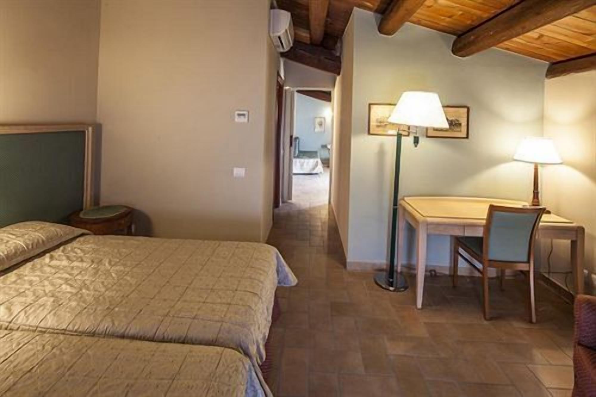 Habitación de hotel con dos camas, un escritorio y una silla, y una lámpara.