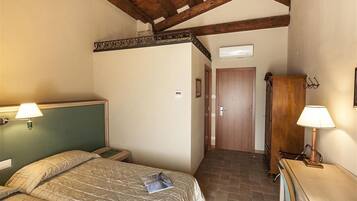Ein Schlafzimmer mit einem Bett, einem Holzschrank, einem Schreibtisch mit Lampe und einer Tür zu einem anderen Raum.
