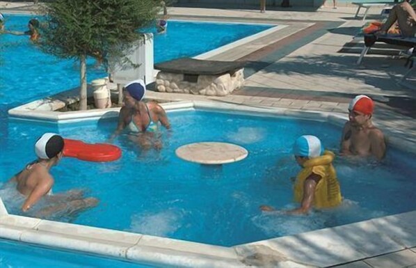 A swimming pool with multiple people, some wearing swim caps and goggles. - Villaggio Verde Cupra (Cupra Marittima)