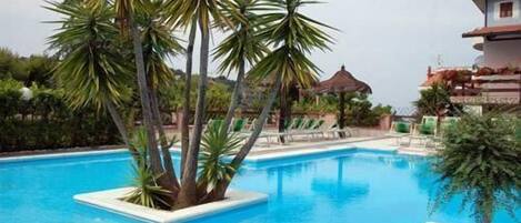 Alberca al aire libre, sombrillas en la alberca y camastros