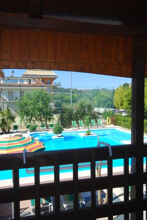 A view of a swimming pool with lounge chairs and a wooden deck. - Villaggio Verde Cupra (Cupra Marittima)