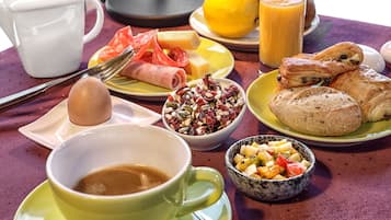 A breakfast table with various food items, a cup of coffee, and a pitcher of orange juice.