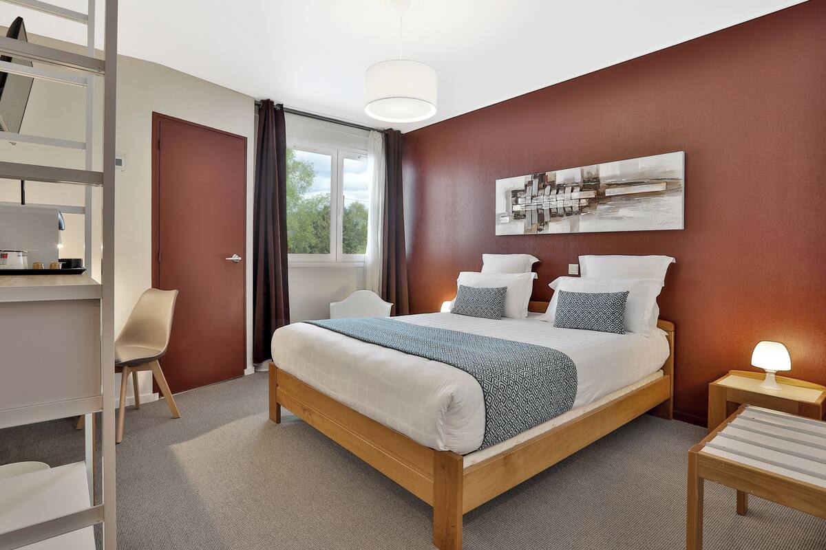 A neatly arranged bedroom with a bed, bedside table, and a desk area.