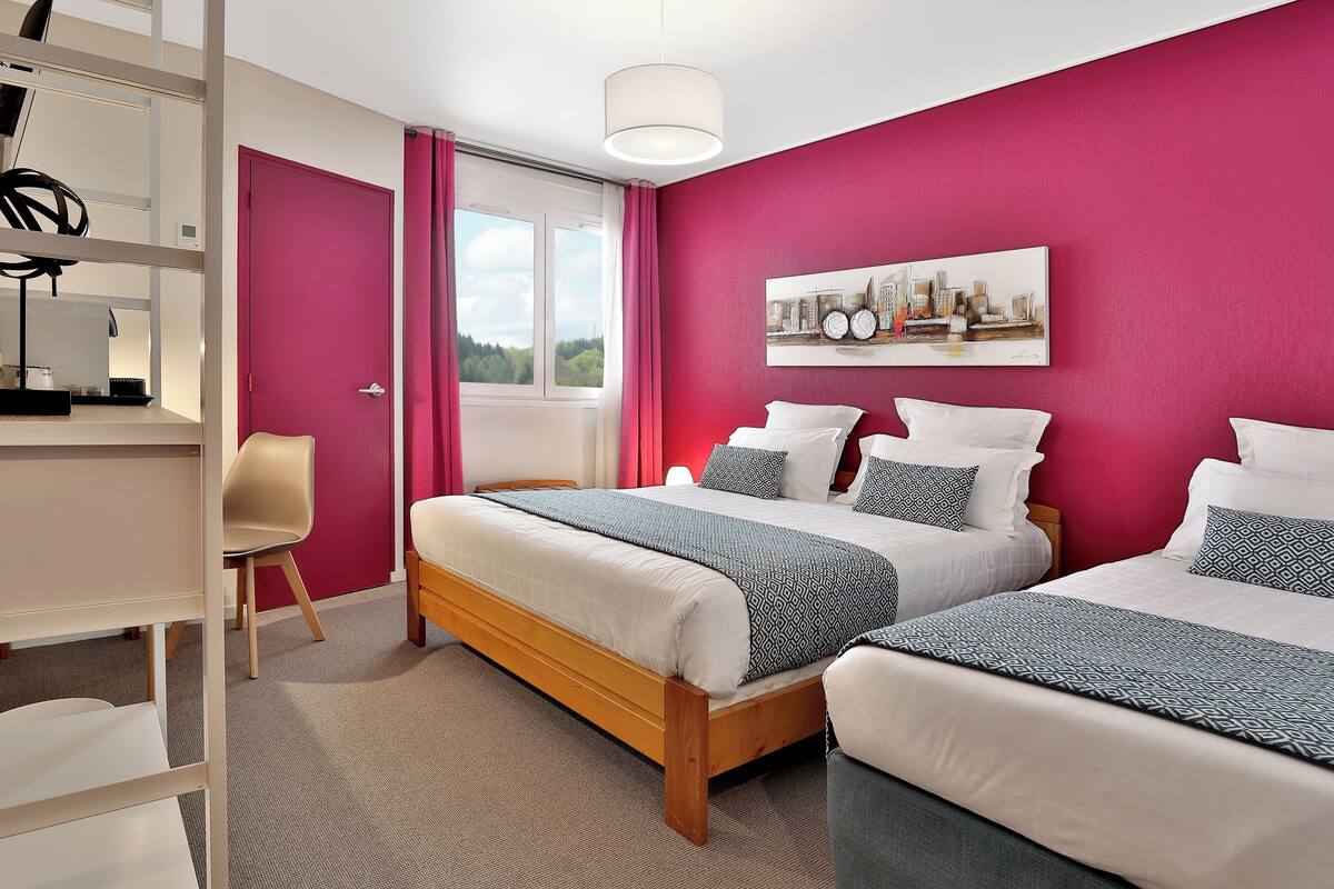 A bedroom with two beds, a desk, and a chair.