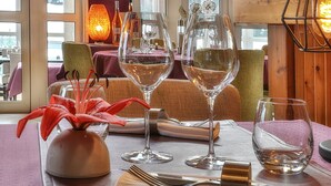 A dining table with wine glasses, cutlery, and a vase with red flowers. - Hôtel Europa (Maussac)