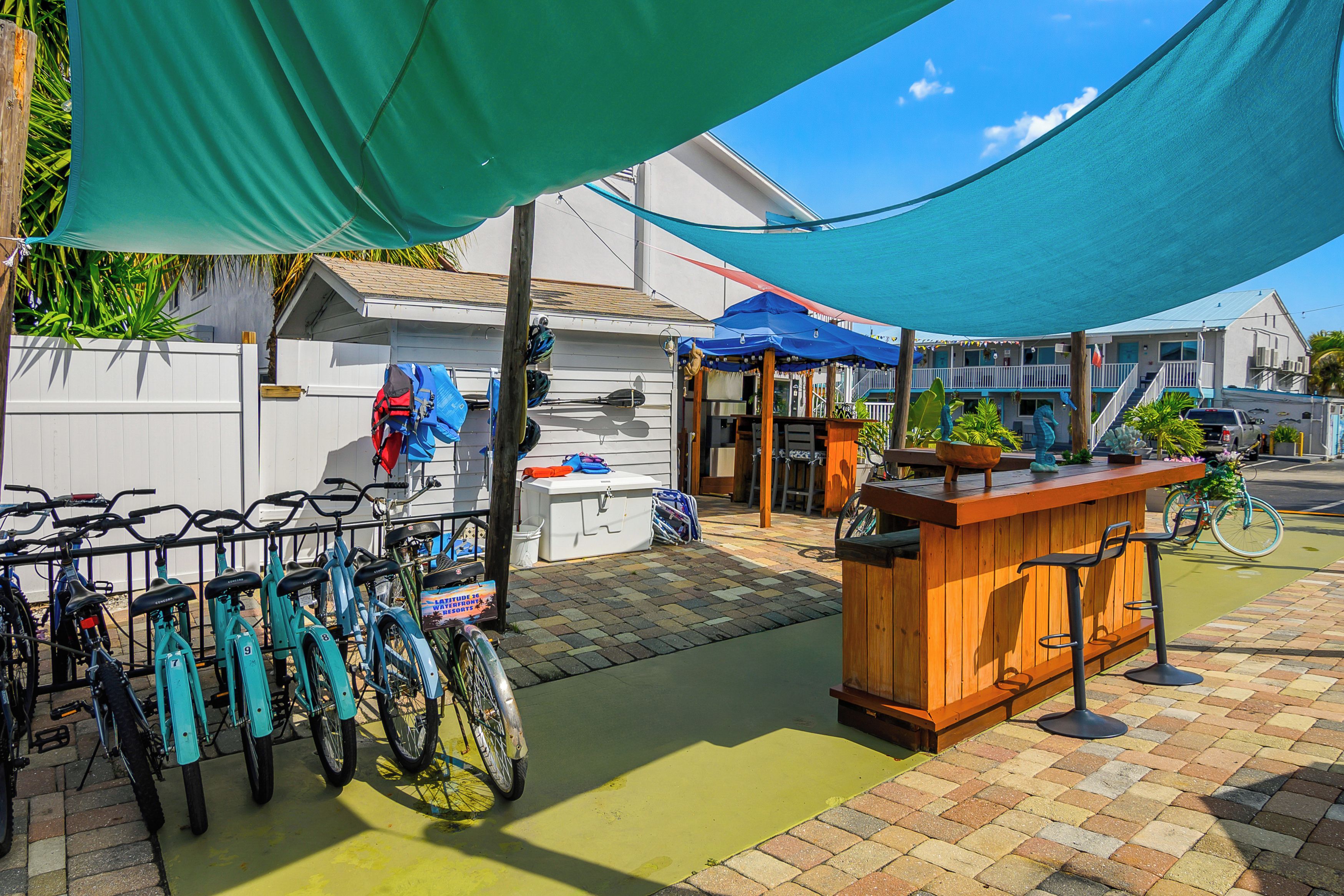 A patio area with a wooden bar, bicycles, and a covered seating area.