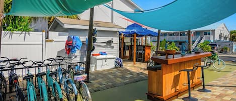 A patio area with a wooden bar, bicycles, and a covered seating area.