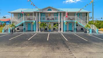 A two-story building with a blue and white color scheme, a parking lot in front, and a flag on the roof.