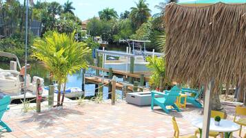 A tropical resort with a dock, lounge chairs, and a thatched umbrella.