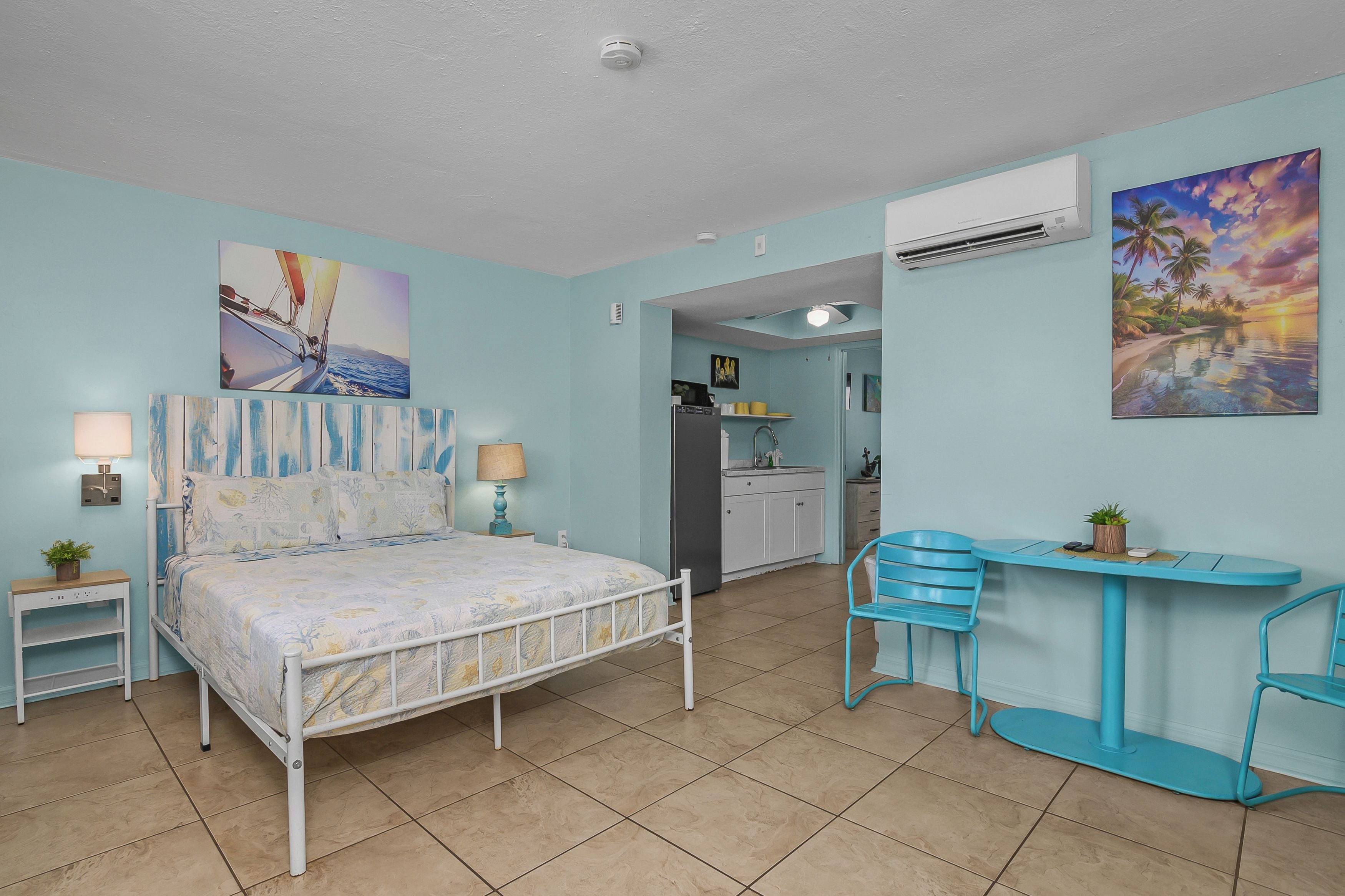 Une chambre à coucher avec un lit, des tables de chevet, un bureau et des chaises.