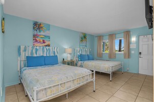 A room with two beds, a window with curtains, and a door with a lock.