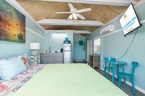 Een kamer met een bed, een plafondventilator, een kitchenette en een bord dat de locatie aangeeft als Latitude 26° Waterfront Resorts.