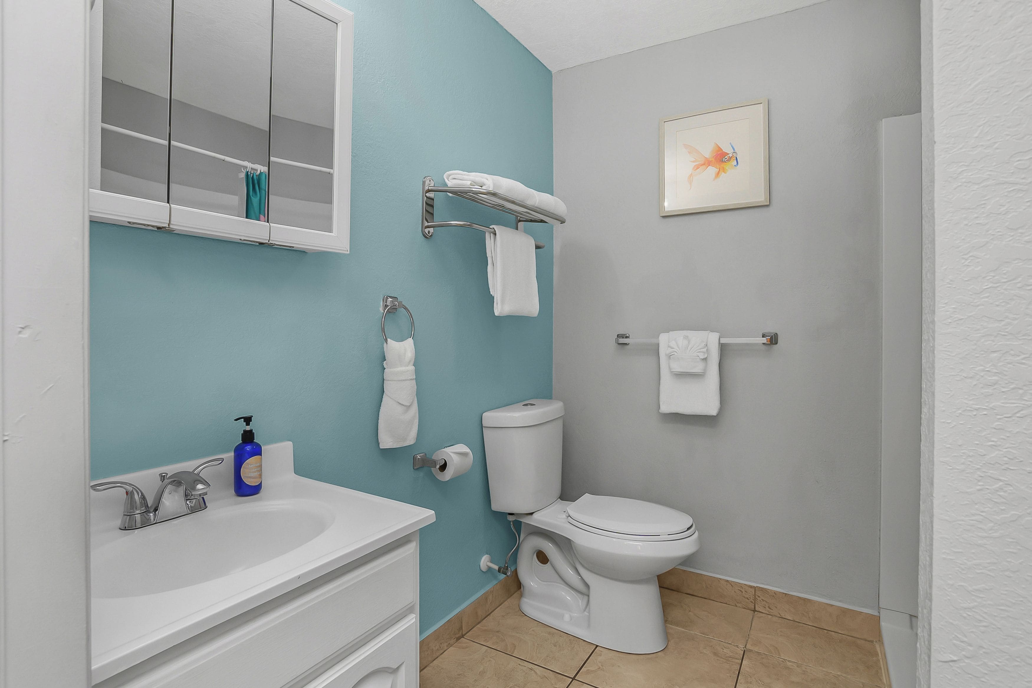 Une salle de bain avec un lavabo blanc, des toilettes et un porte-serviettes.
