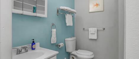 Une salle de bain avec un lavabo blanc, des toilettes et un porte-serviettes.
