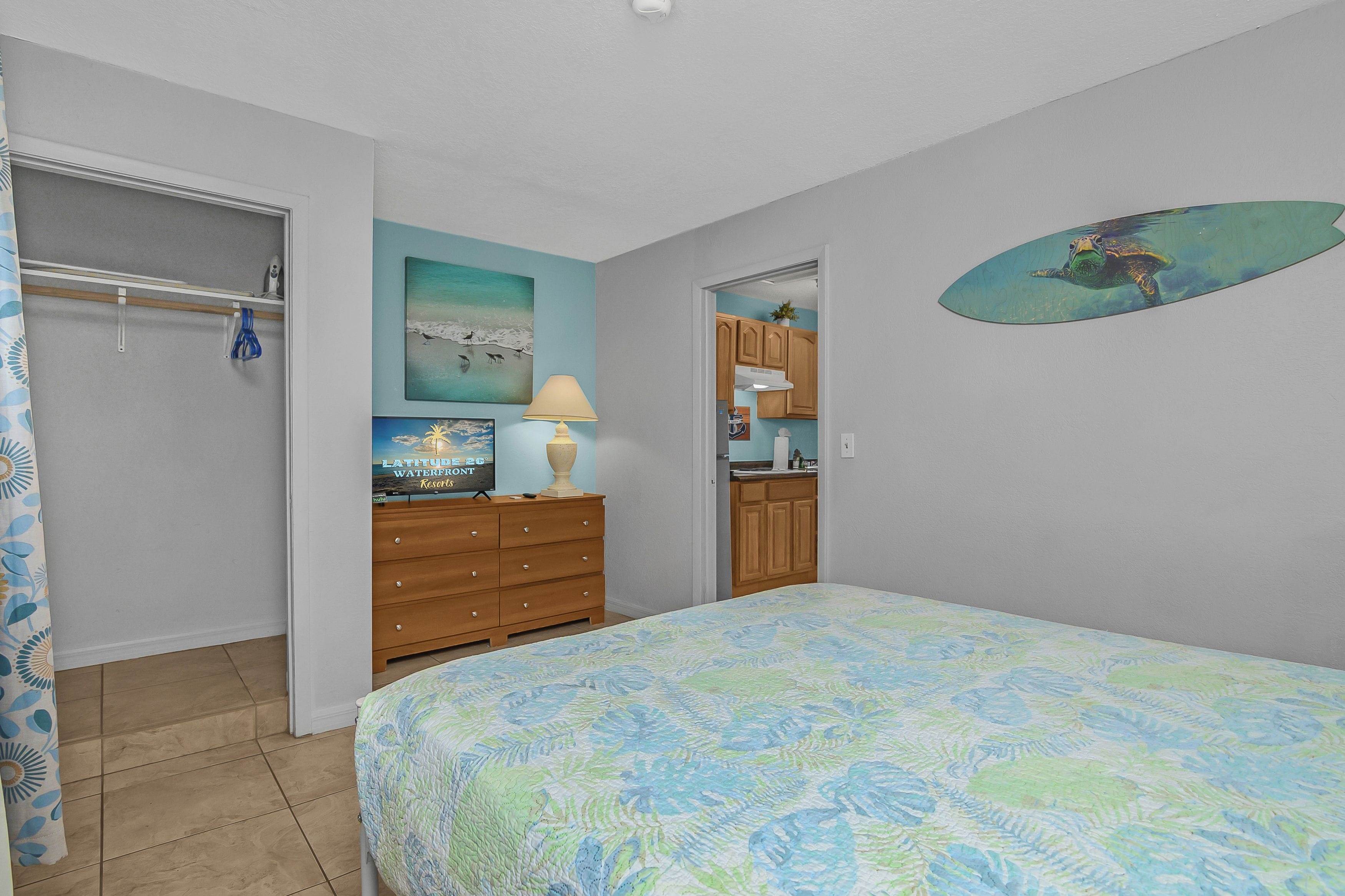 A bedroom with a bed, a dresser, a painting, and a closet.