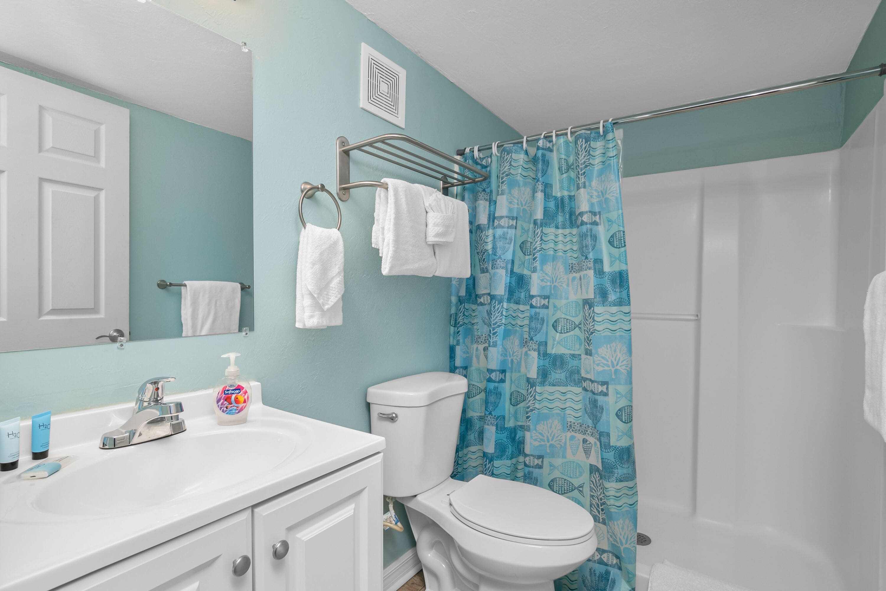 Een badkamer met een witte wastafel, toilet en een douchegordijn met een blauw patroon.