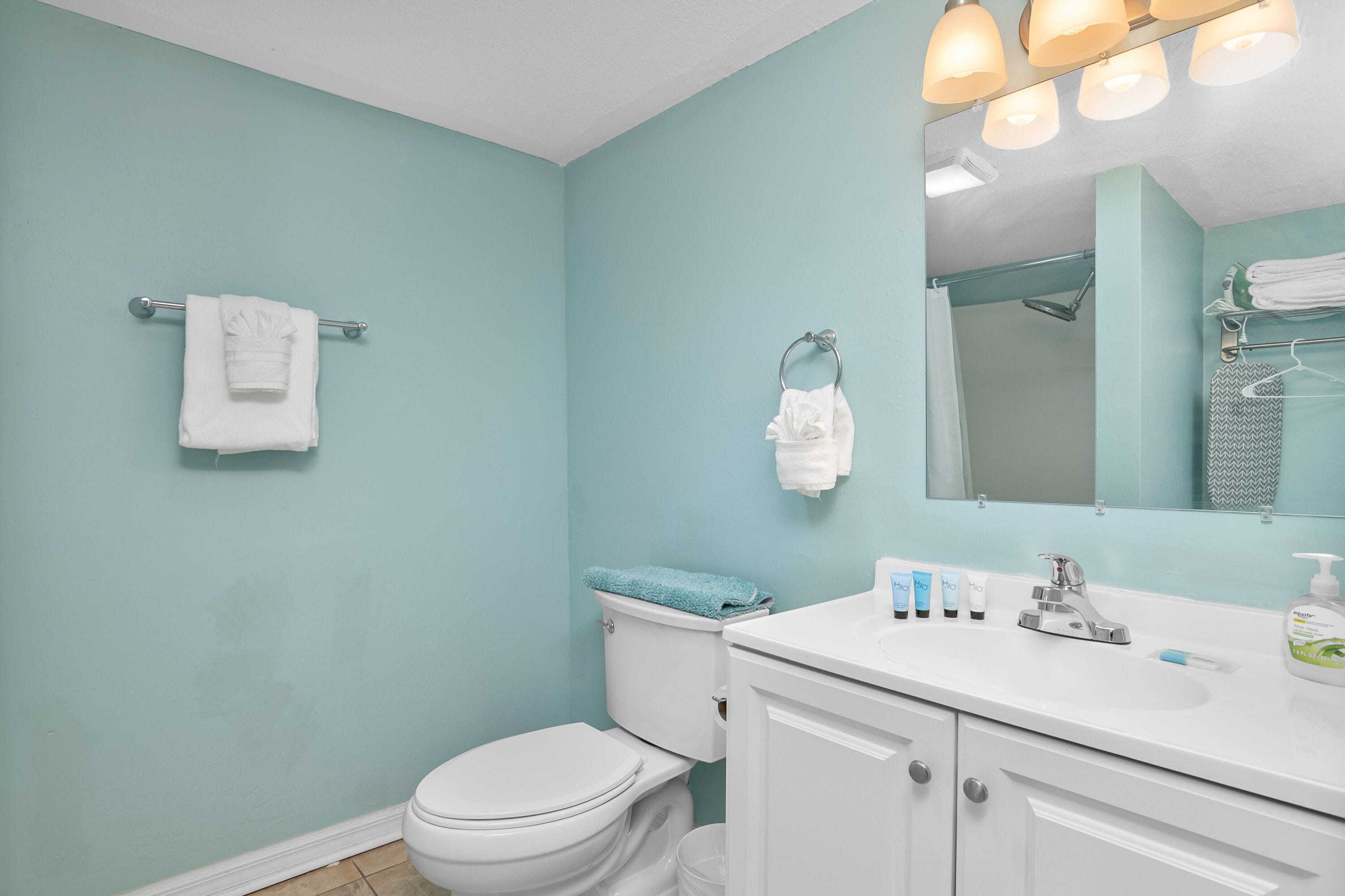 A bathroom with a toilet, sink, and mirror.