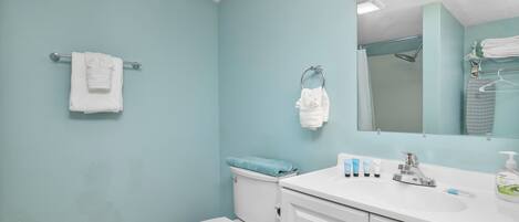 A bathroom with a toilet, sink, and mirror.