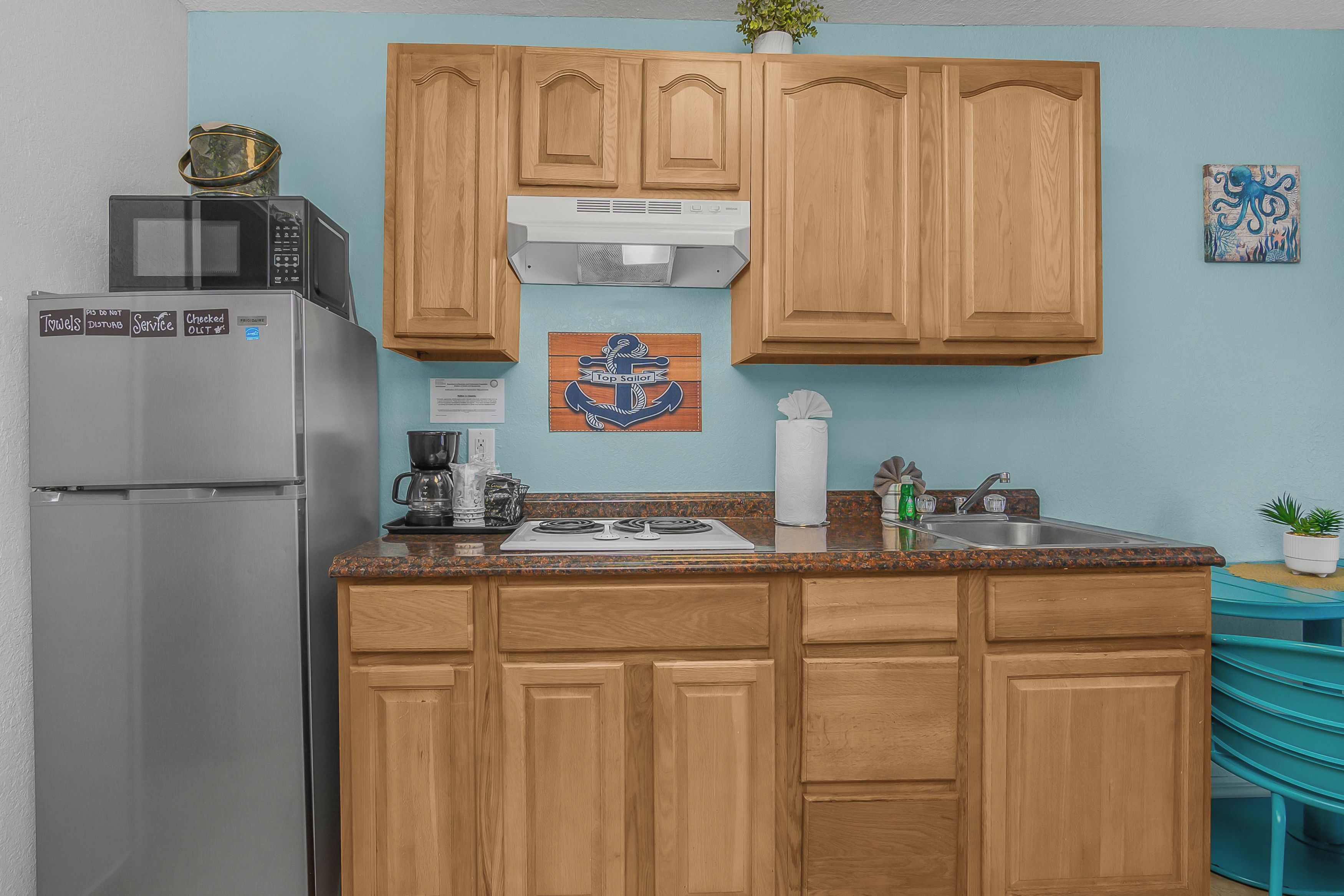Una cocina con gabinetes de madera, un refrigerador de acero inoxidable, un microondas, una estufa y un lavamanos.