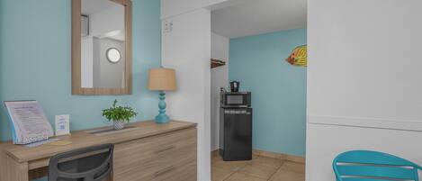 Een hotelkamer met een bureau, stoel en een magnetron.