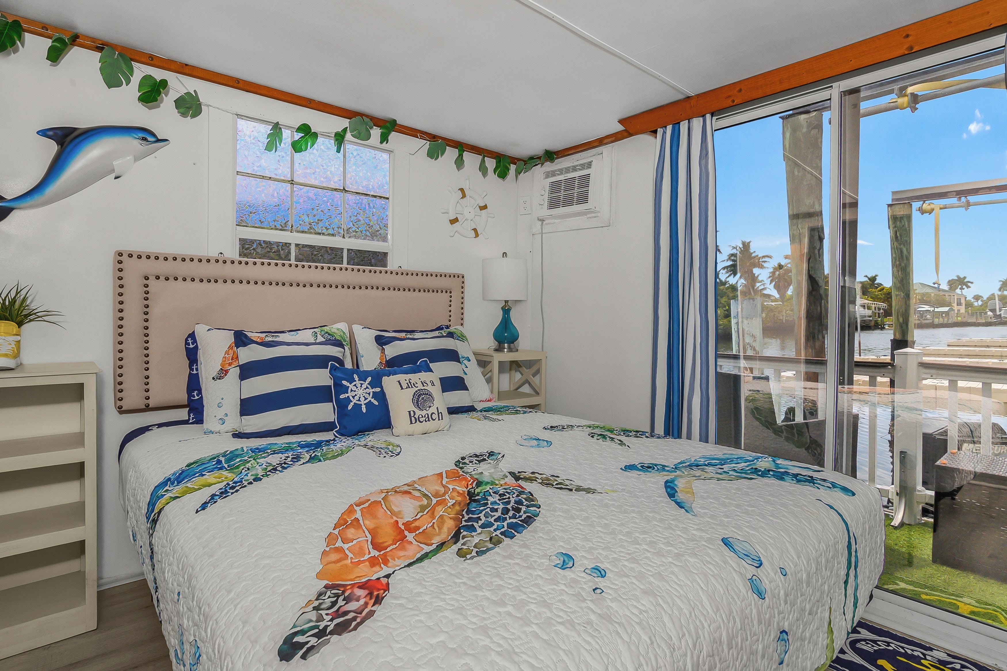 A bedroom with a bed, a window, a wall-mounted plant, and a view of the outdoors.