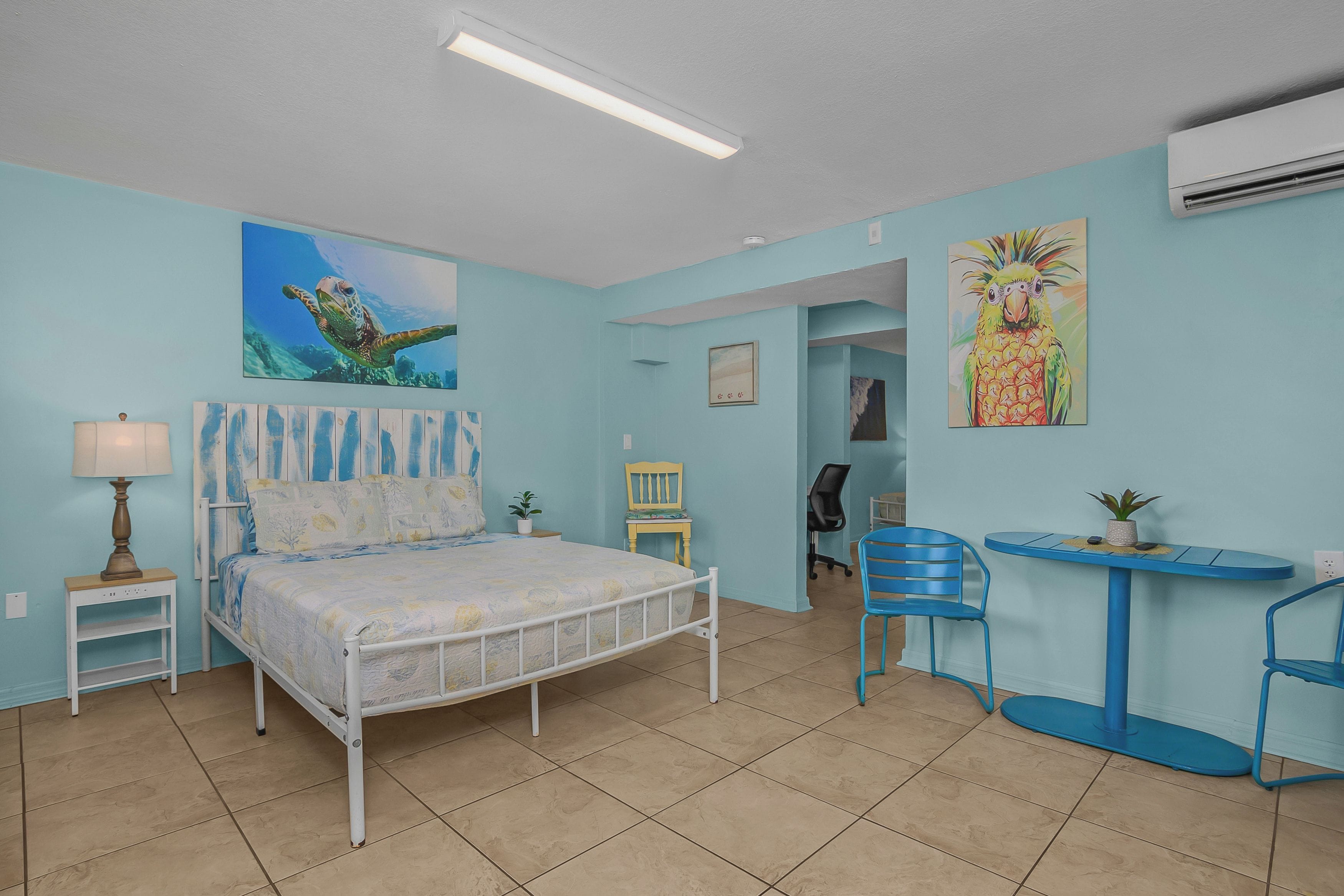 Ein Schlafzimmer mit einem Bett, einem Schreibtisch, Stühlen und Kunstwerken an den Wänden.