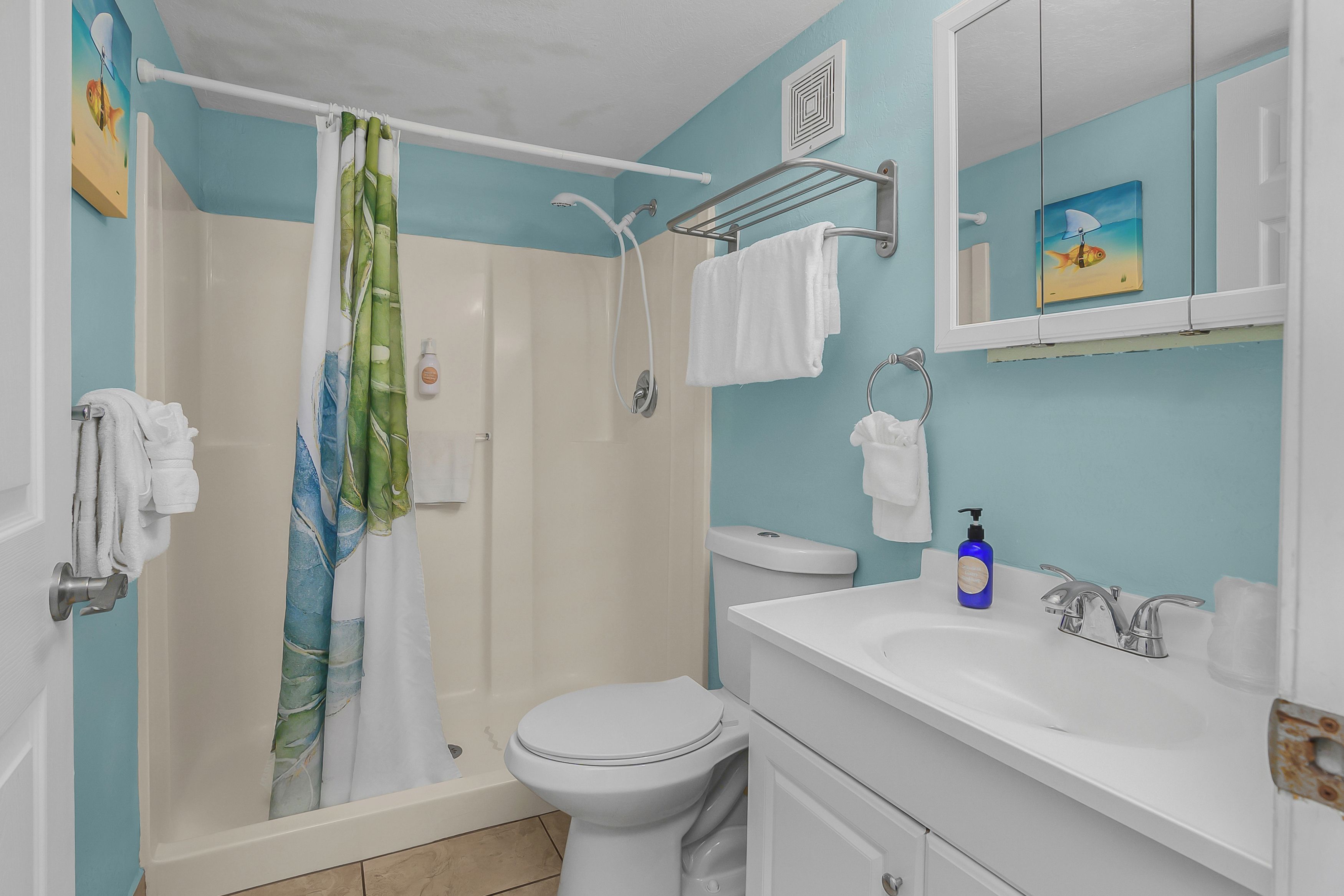 Ein Badezimmer mit Dusche, Toilette, Waschbecken und Handtuchhalter.