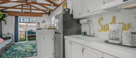 Una cocina moderna con armarios blancos, un refrigerador de acero inoxidable y una cafetera.